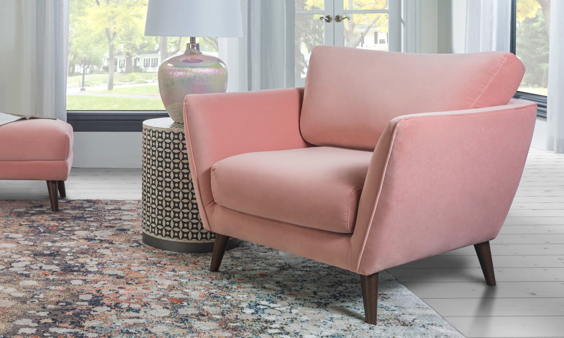 Pink armchair made of velvet upholstery and retro inspired flare arms.